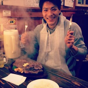 紙エプロンをしてナイフとフォークを持つトレーナー姿の山縣亮太